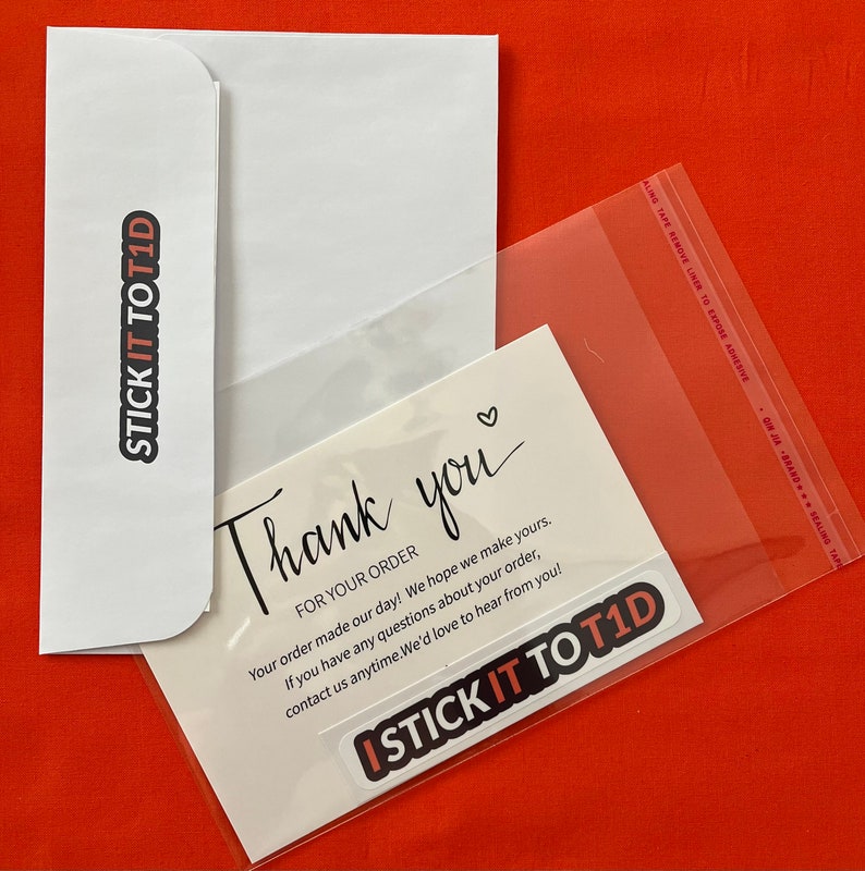 May include: A white envelope with a black sticker that says "STICK IT TO T1D" and a white card with the text "Thank you" and "FOR YOUR ORDER" and "Your order made our day! We hope we make yours. If you have any questions about your order, contact us anytime. We'd love to hear from you!" and a black sticker that says "ISTICK IT TO T1D".
