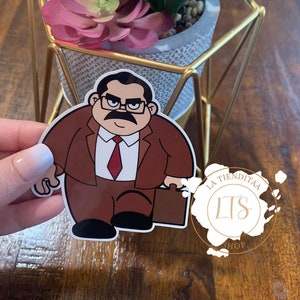 May include: A cartoon sticker of a man in a brown suit and red tie holding a briefcase. The sticker is on a wooden surface with a potted succulent plant in the background. The sticker has the text "La Tiendita LTS Shop" on it.