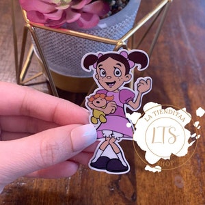 May include: A sticker featuring a cartoon girl in a pink dress holding a teddy bear. The sticker is on a wooden surface and has the text "La Tienditaa LTS Shop" on it.