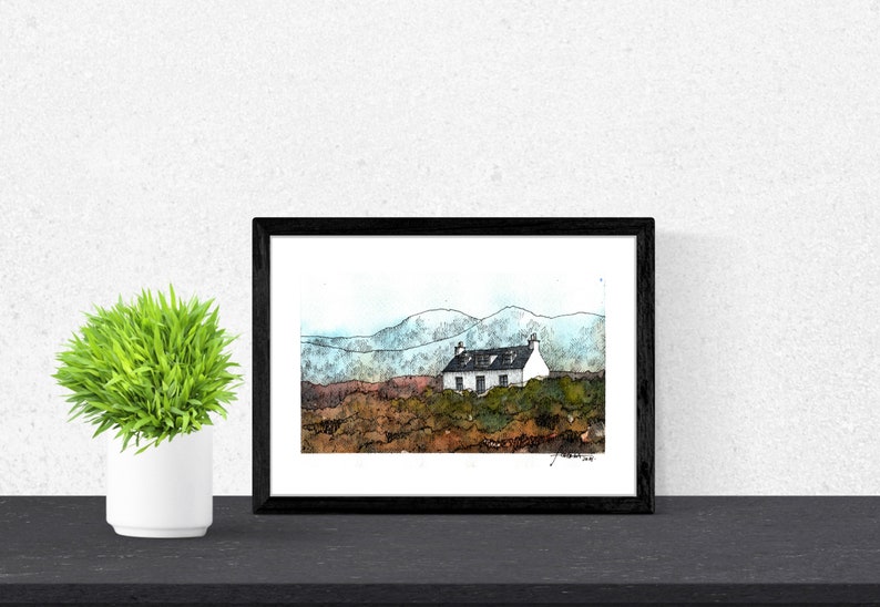 May include: A framed watercolor painting of a white cottage with a black roof, set against a backdrop of blue and green mountains. The cottage is surrounded by brown and green brush.