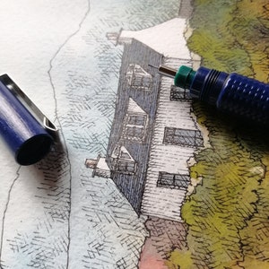 May include: A close-up of a drawing of a white house with a blue roof and a green tree in the background. A blue mechanical pencil is lying on top of the drawing.