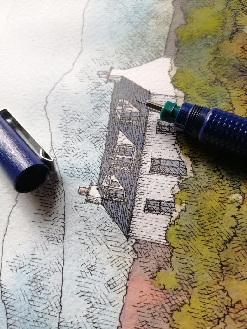 May include: A close-up of a drawing of a white house with a blue roof and a green tree in the background. A blue mechanical pencil is lying on top of the drawing.