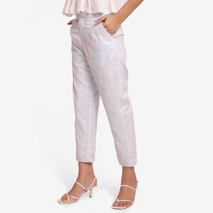 May include: White and blue striped pants with a high waist and a tailored fit. The pants have a straight leg and are cuffed at the ankle. The model is wearing white strappy heels. The pants have pockets.