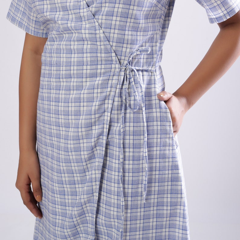 May include: A white and blue plaid wrap dress with a tie at the waist.
