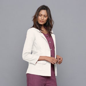 May include: A white blazer with a single button fastening and a pocket on the left side. The blazer has long sleeves and a collar.