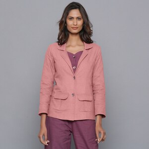 May include: A dusty rose blazer with two front pockets and a two-button closure. The blazer is paired with a purple top and pants. The outfit is a casual, yet stylish ensemble.