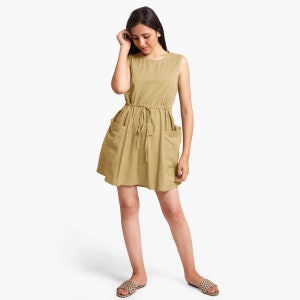 Könnte beinhalten: Ein hellbraunes, ärmelloses Kleid mit einem Kordelzug in der Taille und zwei Taschen. Das Kleid ist aus einem weichen, bequemen Stoff gefertigt und hat eine lockere Passform.