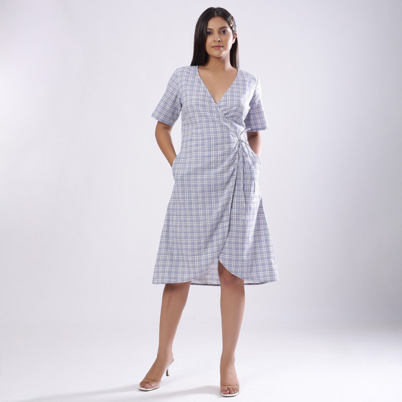 May include: A blue and white plaid wrap dress with a V-neckline and short sleeves. The dress has a tie at the waist and pockets on the sides.