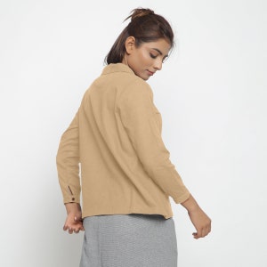 May include: A light brown long-sleeved shirt with a collared neckline and button closure. The shirt has a relaxed fit and is made of a soft, comfortable fabric.