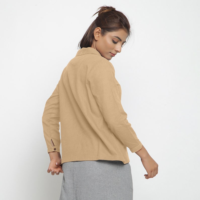 May include: A light brown long-sleeved shirt with a collared neckline and button closure. The shirt has a relaxed fit and is made of a soft, comfortable fabric.