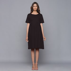 May include: A simple black midi dress with a round neckline and short sleeves. The dress has a slightly A-line silhouette.