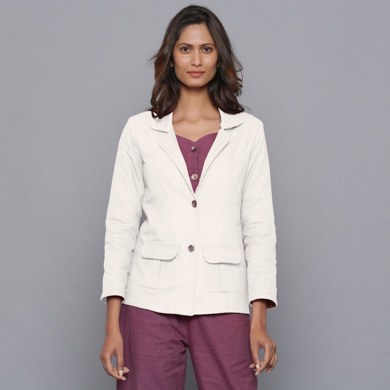 May include: A white linen blazer with a notched collar, two front pockets, and a button closure. The blazer has a relaxed fit and is perfect for layering.