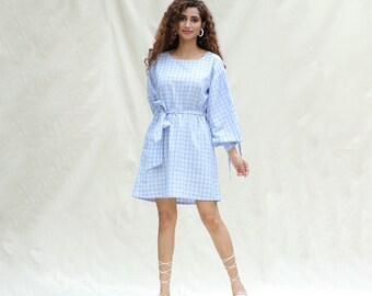 May include: A light blue and white checkered dress with a tie belt and puffed sleeves. The dress is knee-length and has a round neckline.