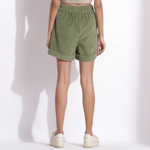 May include: Green corduroy shorts with a wide elastic waistband and a cuffed hem.