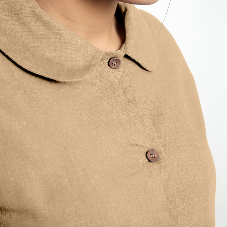 May include: A close-up of a brown linen shirt with a peter pan collar and two brown buttons.
