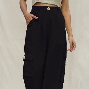 May include: Black cargo pants with multiple pockets and a button closure.