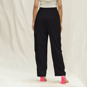 May include: Black cargo pants with a drawstring waist and multiple pockets. The pants are shown from the back.