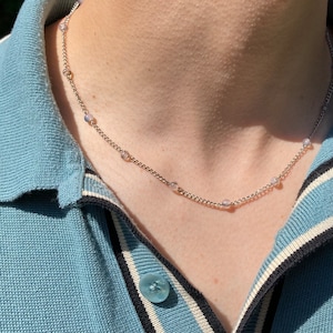 May include: A silver chain necklace with small, round, light purple beads.
