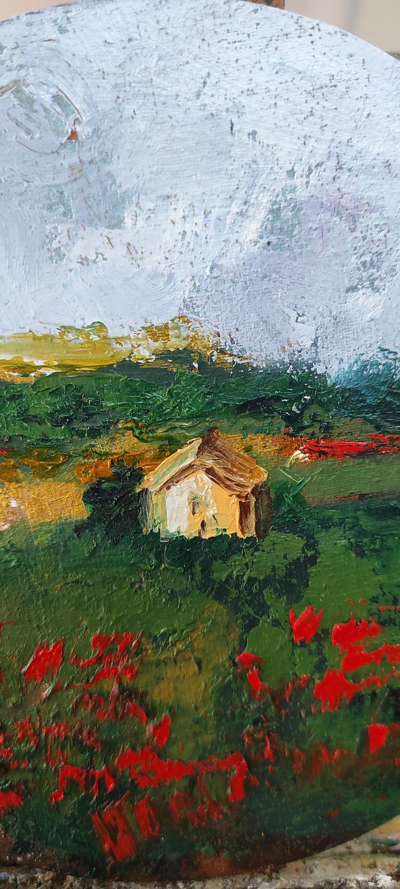 Op de afbeelding: Een schilderij van een klein huis in een veld met rode bloemen op de voorgrond. De lucht is bewolkt en het huis is geschilderd in tinten geel en bruin.