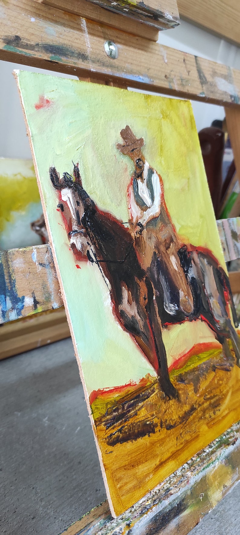 May include: Oil painting of a cowboy on horseback. The artwork features a brown horse and a rider in a hat and vest. The background is a blend of yellow and green, with a touch of red.