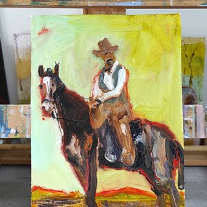 May include: Oil painting of a cowboy on horseback. The artwork features a cowboy in a brown hat and vest, riding a brown horse. The background is a blend of yellow and orange hues, suggesting a sunset or desert landscape.