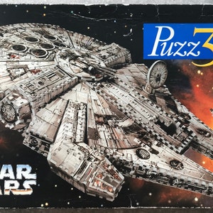 May include: A Star Wars Puzz3D puzzle box depicting the Millennium Falcon spacecraft against a space backdrop. The box features the Star Wars logo at the bottom and the Puzz3D logo at the top right.