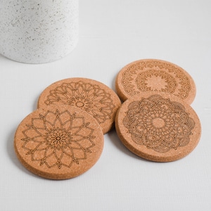 May include: Four round cork coasters with intricate laser-cut mandala designs. The coasters are made of natural cork and feature a variety of geometric patterns.