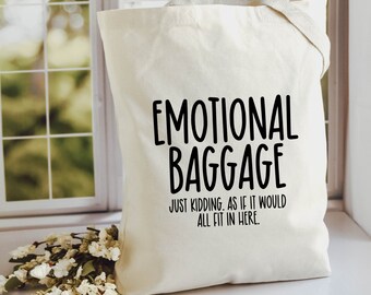 May include: A white canvas tote bag with black text that reads "Emotional Baggage Just Kidding, as if it would all fit in here."