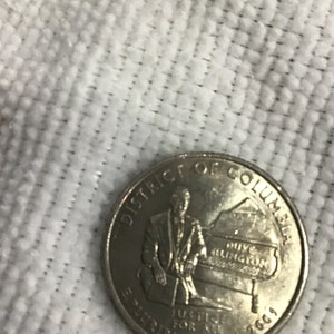 Może przedstawiać: Srebrna moneta o nominale 25 centów przedstawiająca portret Duke'a Ellingtona grającego na pianinie z tekstem "District of Columbia" i "E Pluribus Unum" wokół krawędzi. Na monecie widnieje również tekst "Justice for All" i rok "2003".