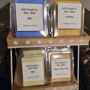 May include: Four wax melts in clear plastic containers. The wax melts are in the scents Bleu, Drakkar, Chai, and Brown Sugar & Fig. Each container has a label with the name of the scent and the weight of the wax melt, 2.5 ounces.