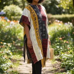 May include: A patterned tunic in mustard yellow, black, white, and burgundy. The tunic has a V-neck and short sleeves. The person is wearing black leggings and brown sandals. A small woven basket is held in the hand. The background is a garden.