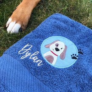 May include: Blue dog-themed towel with the name "Dylan" embroidered on it. The towel features a cartoon dog with a red collar and paw prints.