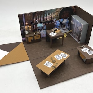 Könnte beinhalten: Ein Miniatur-Diorama-Set, das einen braunen Raum mit einem gedruckten Hintergrund eines Zaubertrankladens darstellt. Das Set enthält einen kleinen Tisch, einen Stuhl, einen Schrank und einen Schreibtisch, arrangiert mit winzigen Metallschlüsseln.