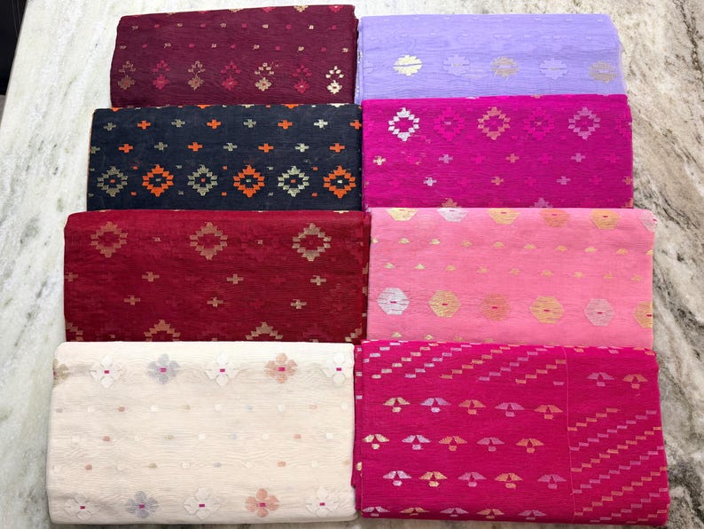 May include: An assortment of colorful fabric pieces, each folded and displaying a unique pattern. The fabrics vary in shades of red, pink, purple, and blue, with intricate geometric and floral designs. The textiles are likely suitable for sewing or crafting projects.