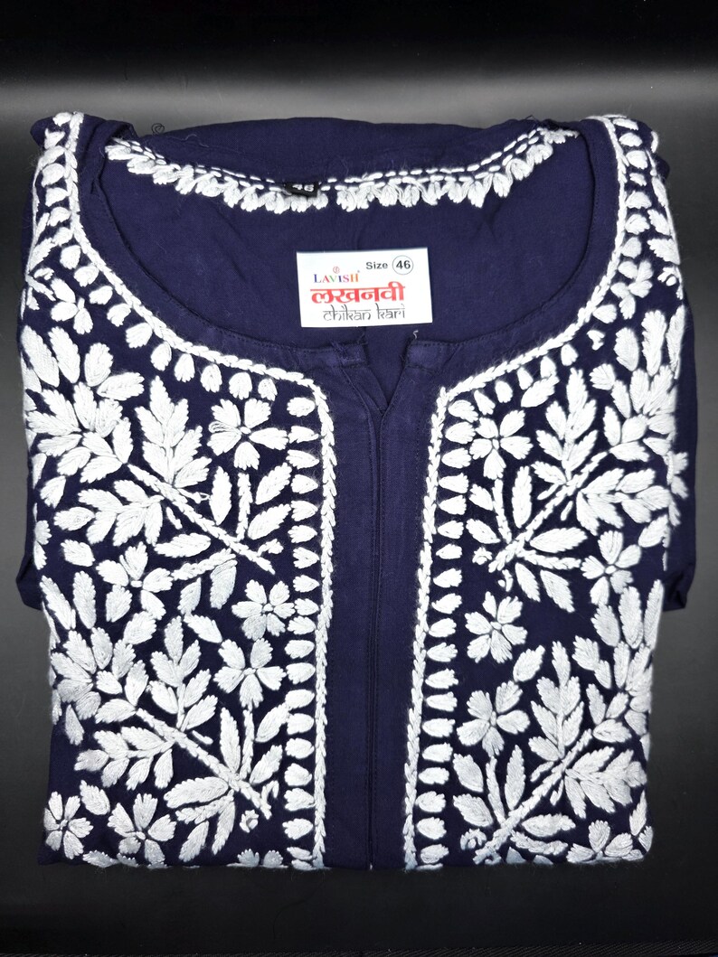 May include: Navy blue tunic with intricate white floral embroidery. The tunic features a round neckline and a split front. A label with text is visible near the neckline. Size 46.