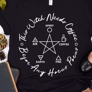 Pode incluir: Camiseta preta com um gráfico branco que diz "This Witch Needs Coffee Before Any Hocus Pocus" com um pentagrama e os elementos de terra, ar, fogo, espírito e café.