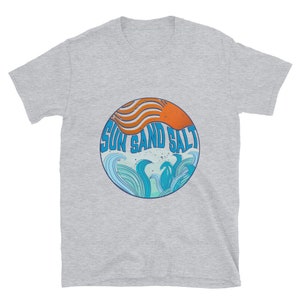 May include: Gray short-sleeved t-shirt with a circular graphic design featuring a stylized orange sun, blue waves, and the text "Sun Sand Salt".
