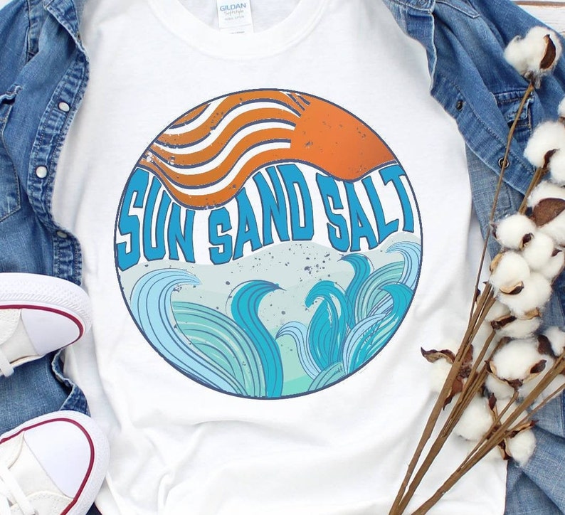 May include: White t-shirt with a round graphic design featuring a sun, waves, and the text "Sun Sand Salt".
