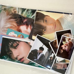 May include: A collection of photo cards featuring various images of young men. The cards are arranged in a clear plastic sleeve.