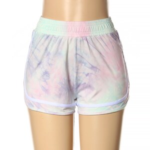 May include: White athletic shorts with a tie-dye pattern in shades of pink, purple, and blue. The shorts have a white elastic waistband and white trim around the legs.