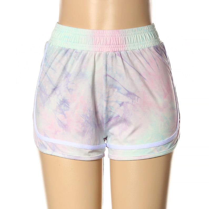 May include: White athletic shorts with a tie-dye pattern in shades of pink, purple, and blue. The shorts have a white elastic waistband and white trim around the legs.