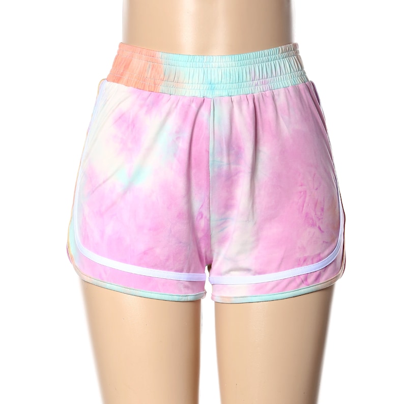 May include: Pink tie-dye shorts with white trim. The shorts have an elastic waistband and a relaxed fit.