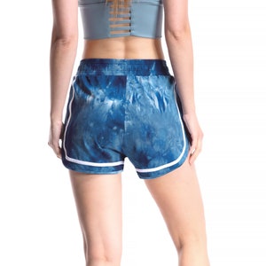 May include: Blue and white tie-dye athletic shorts with white trim. The shorts have a drawstring waistband.
