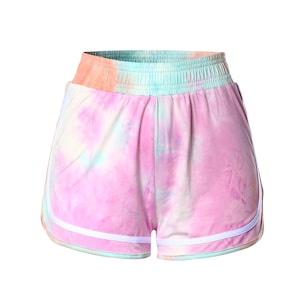 May include: Tie-dye shorts with a white trim around the edges. The shorts are a light pink color with blue and green tie-dye patterns.
