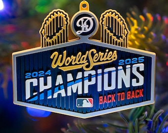May include: A blue, white, and gold World Series Champions ornament. The ornament features the text "World Series Champions 2024 2025 Back to Back" and the MLB logo. The top has a gold loop for hanging and a team logo.