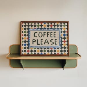 May include: A framed sign with the words "COFFEE PLEASE" in black letters. The sign has a colorful checkered pattern and is displayed on a green and tan shelf. The shelf is mounted on a white wall.