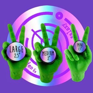 May include: Three green hands holding different sized ear gauges. The gauges are black with iridescent purple and blue accents. The gauges are labeled "Large 2.5", "Medium 2", and "Mini 1.5".