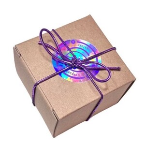 Peut inclure: Une petite bo&icirc;te cadeau carr&eacute;e en carton brun, attach&eacute;e avec une ficelle m&eacute;tallique violette. Un autocollant circulaire iris&eacute; avec le texte "Garden & Galaxy" est appos&eacute; sur le dessus de la bo&icirc;te. La bo&icirc;te est ferm&eacute;e et pr&ecirc;te &agrave; &ecirc;tre offerte.