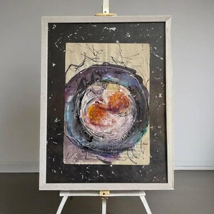 Può includere: Un dipinto astratto incorniciato con un design circolare in tonalità di viola, arancione e bianco su uno sfondo nero. Il dipinto è incorniciato in una cornice di legno bianca ed è esposto su un cavalletto bianco.
