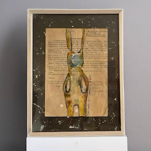 Può includere: Un dipinto ad acquerello incorniciato di una figura umana stilizzata con un cerchio blu per la testa. La figura è dipinta in tonalità di giallo, arancione e verde. Il dipinto è su un pezzo di carta con testo stampato. Il testo è sfocato e difficile da leggere.